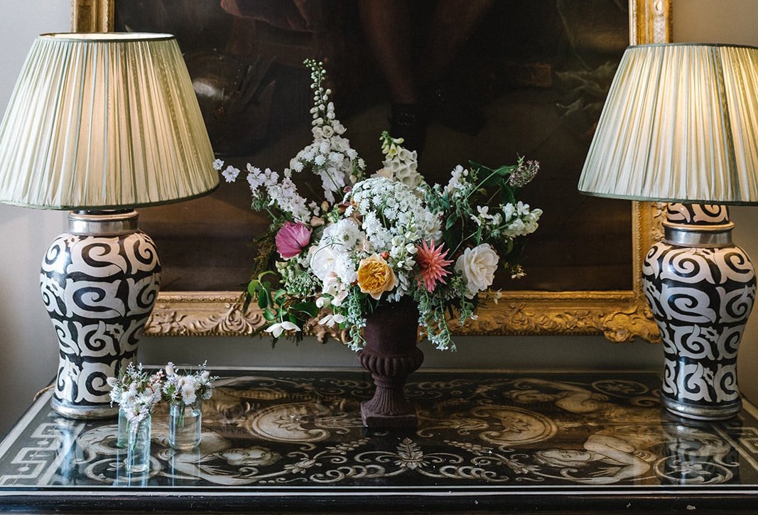 Beautiful flowers on a decorative table with two ornate lamps either side